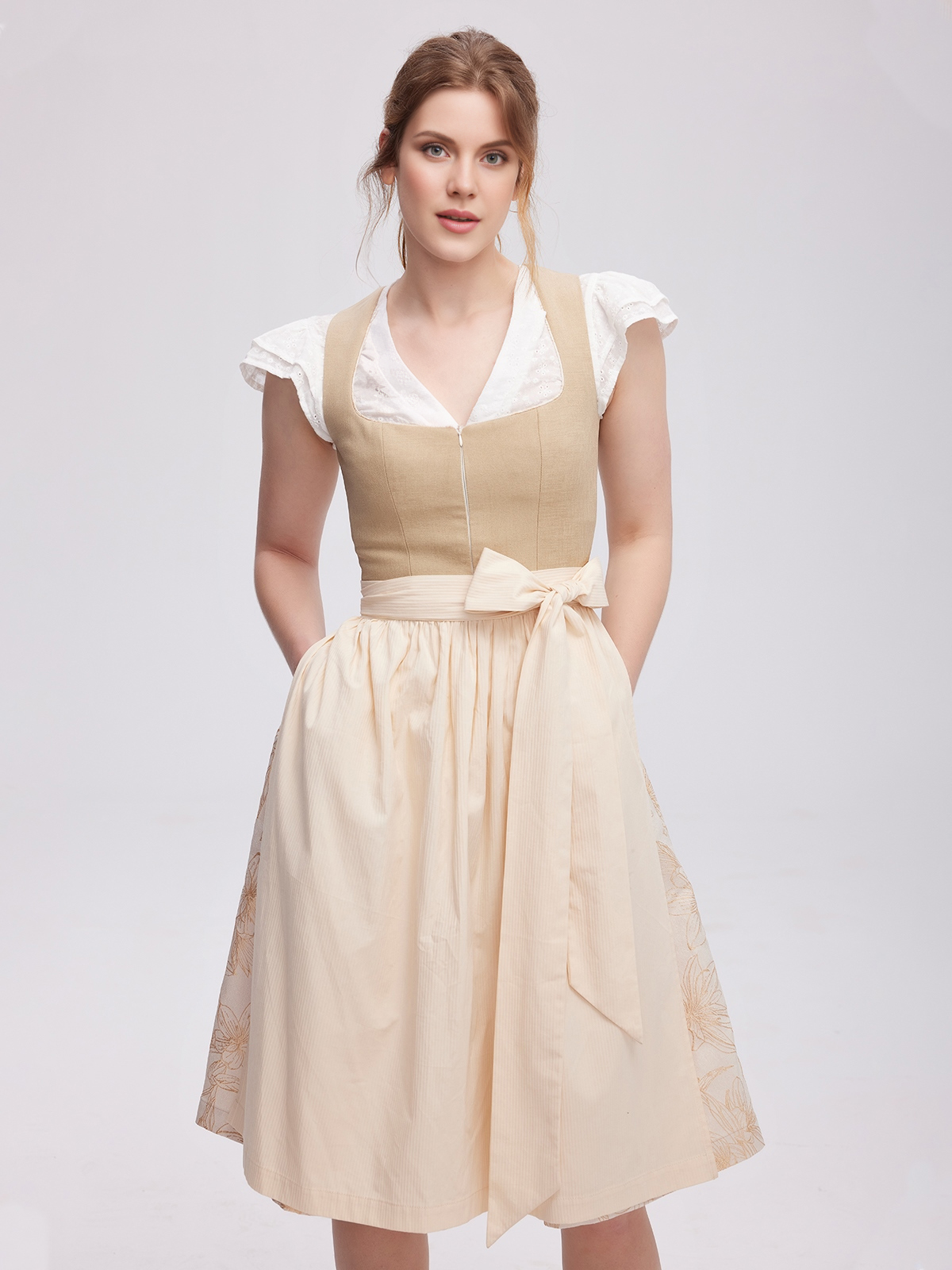 Ein modernes braunes Dirndl mit weißer Bluse und passendem Schmuck